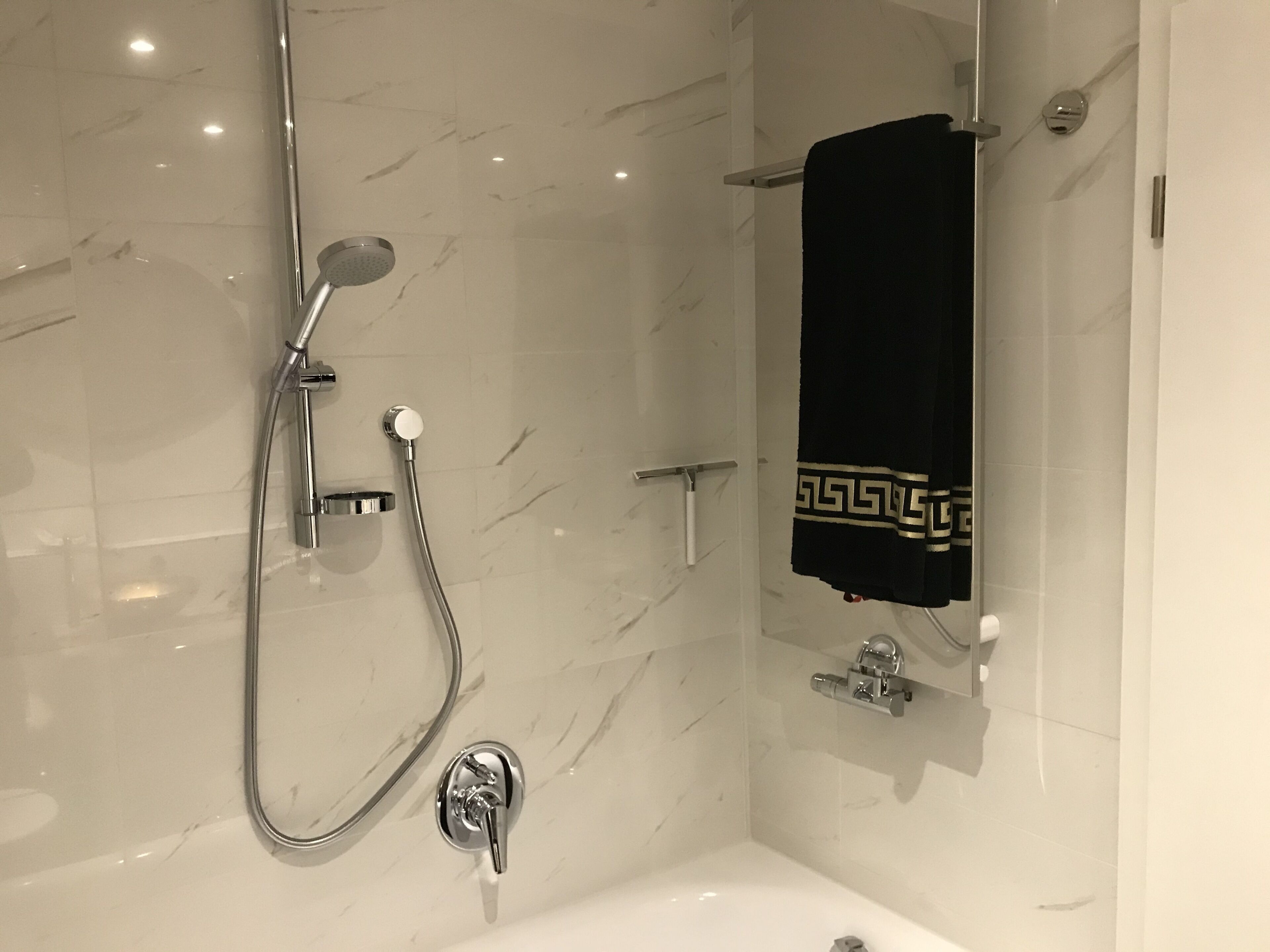 Ein modernes Badezimmer mit Dusche, Badewanne und Handtuchhalter.