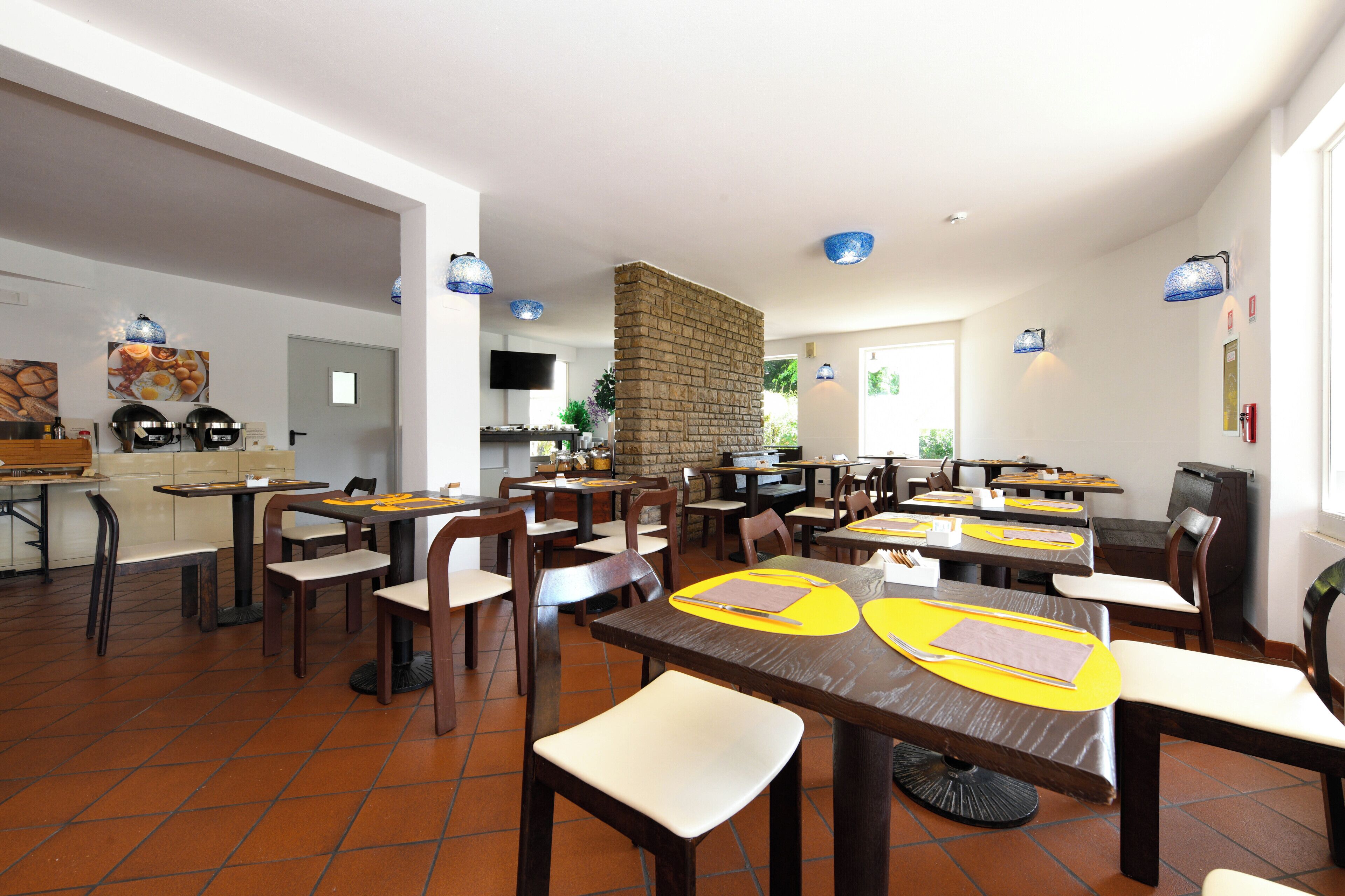 Un restaurante con varias mesas, sillas y una zona de cocina.
