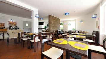 Un restaurante con varias mesas, sillas y una zona de cocina.