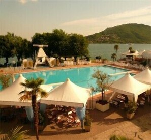 Una piscina al aire libre, sombrillas, sillones reclinables de piscina