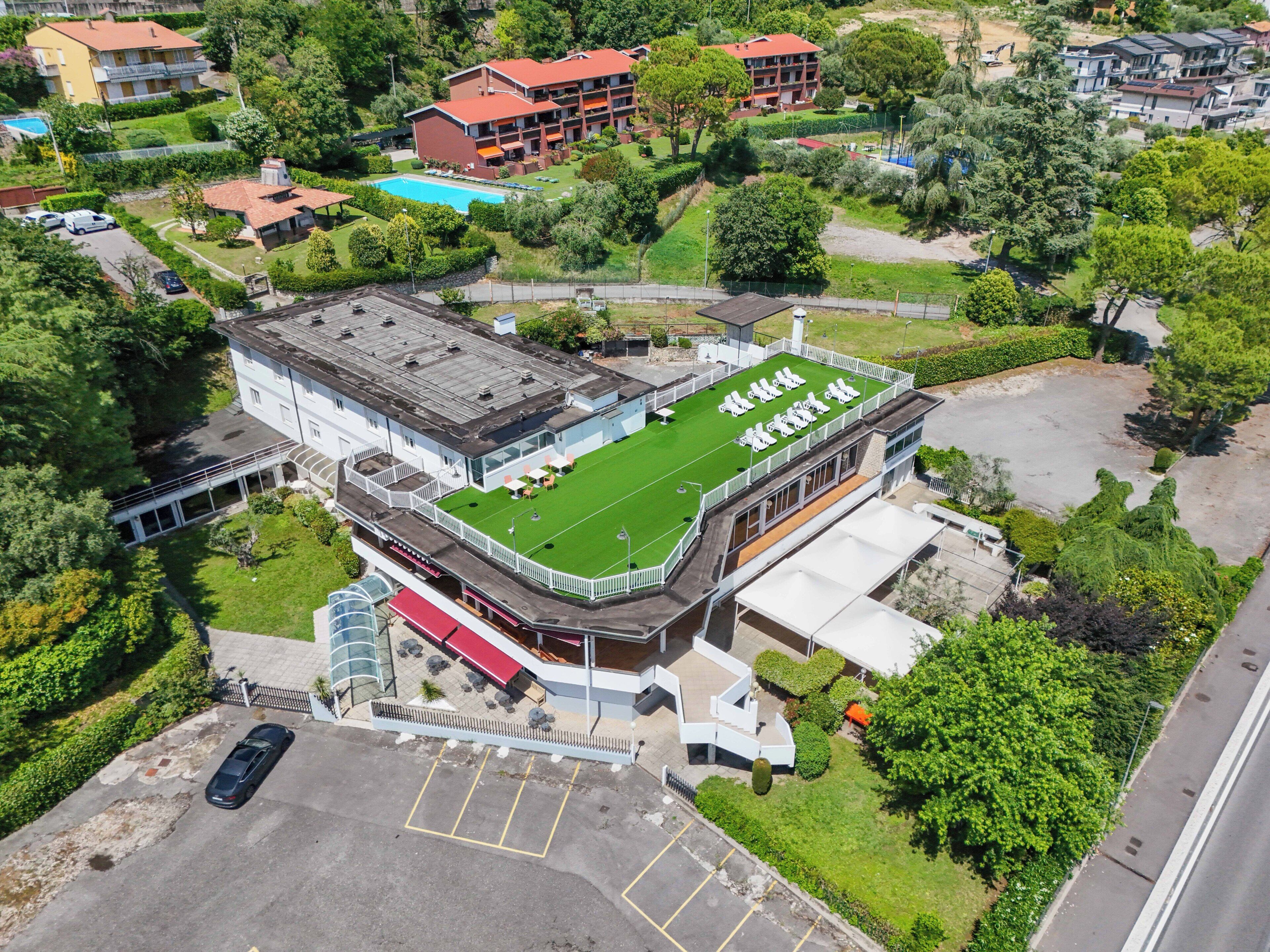 A hotel with a rooftop terrace, a swimming pool, and a parking area.