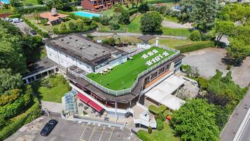 A hotel with a rooftop terrace, a swimming pool, and a parking area.
