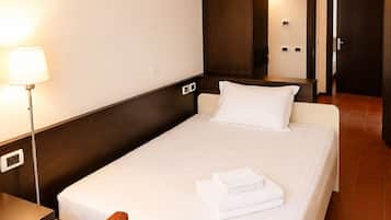 Ein Hotelzimmer mit Bett, Schreibtisch, Stuhl, Lampe und einer Tür.