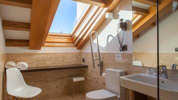 A modern bathroom with a skylight, a toilet, a sink, and a chair.