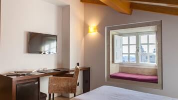 Una habitación de hotel con una cama, un escritorio, una silla, un televisor y una ventana con vistas.