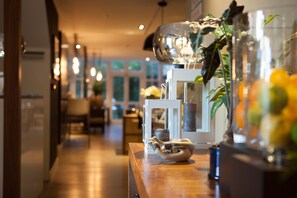 Un pasillo bien iluminado con decoración moderna, que incluye una mesa de madera con adornos y una lámpara colgante.