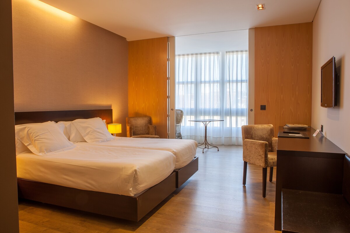 Una habitación de hotel con una cama grande, un escritorio, una silla y un televisor.