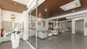A modern lobby with a reception desk, white sofas, a glass partition, and a wooden ceiling. - Hotel Comendador (Bombarral)