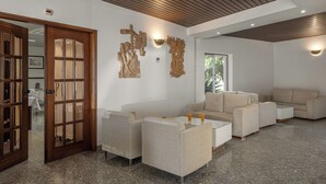 A modern living room with a wooden ceiling, a glass coffee table, and a beige sofa. - Hotel Comendador (Bombarral)