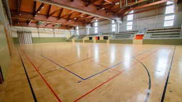 Eine Sporthalle mit Holzboden, Basketballfeldmarkierungen und Rängen.