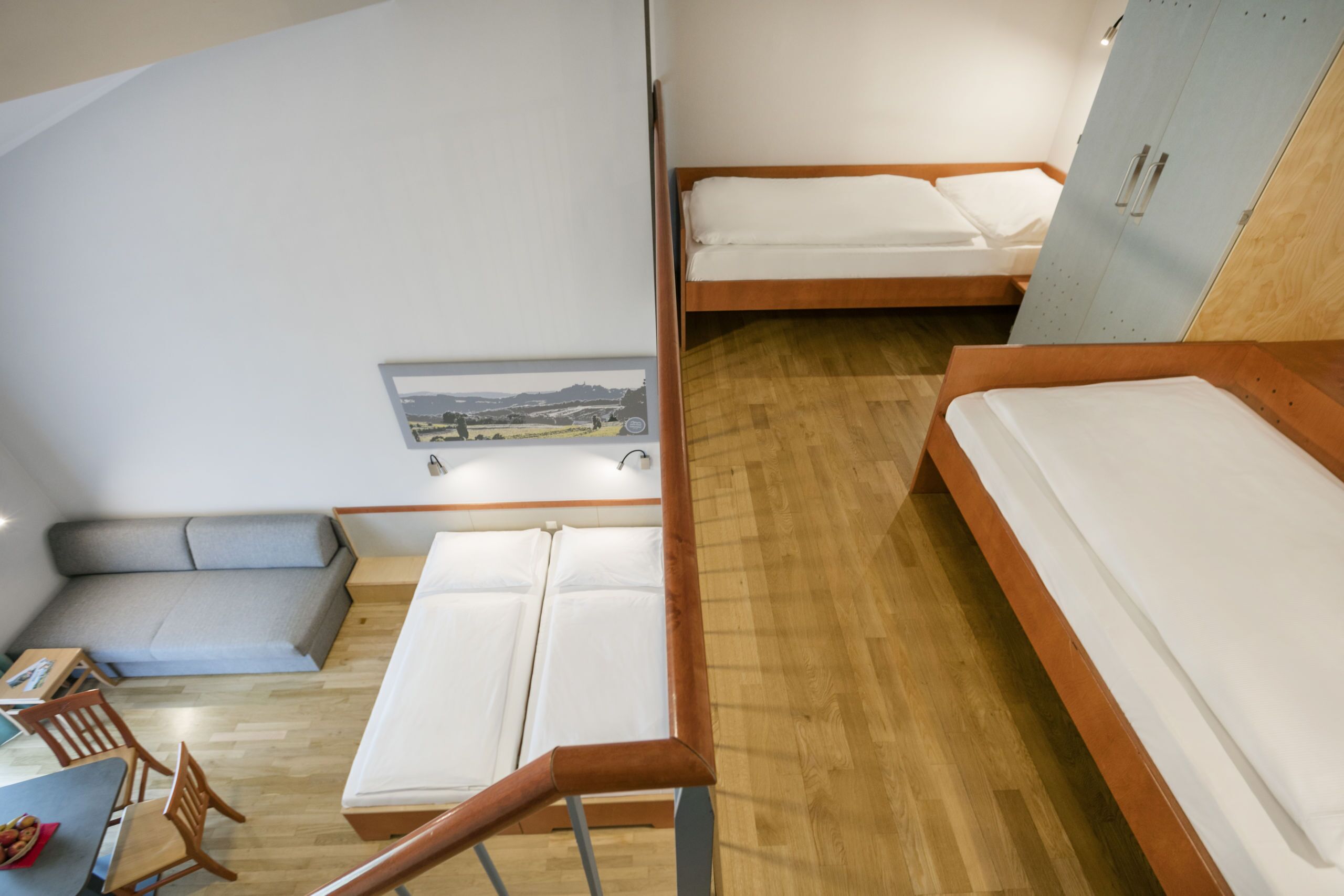 A compact room with two beds, a small seating area, and a desk.