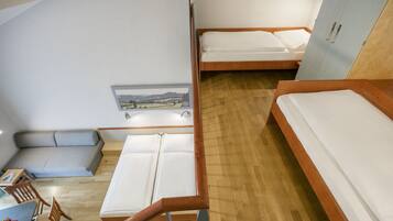 A compact room with two beds, a small seating area, and a desk.