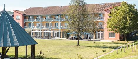 A hotel with a red facade, multiple balconies, and outdoor seating areas.