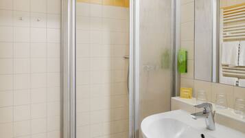A bathroom with a glass-enclosed shower, a white sink, and a mirror above it.