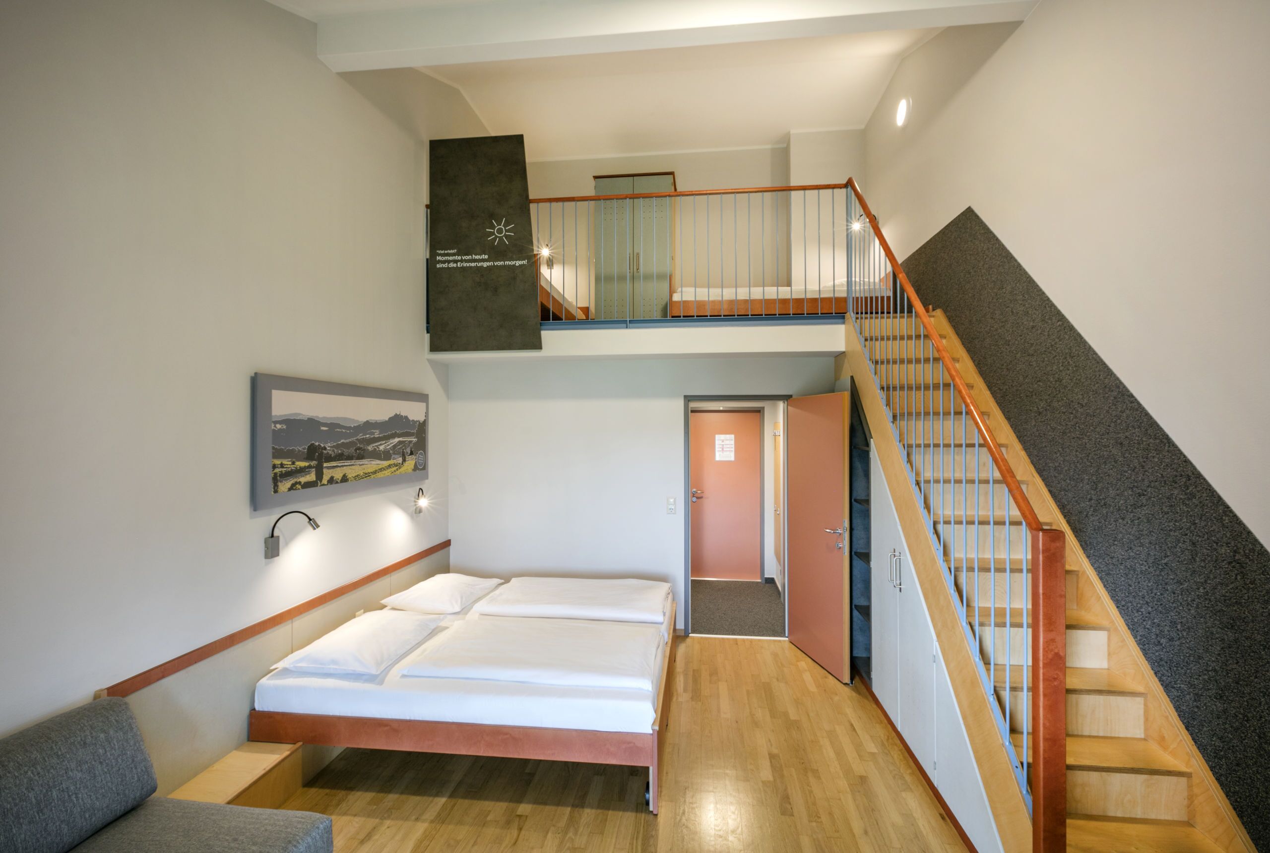 Ein Schlafzimmer mit Bett, Sofa, Treppe und Flur.