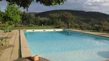 Relax by the serene pool surrounded by lush greenery and a scenic hilly landscape.