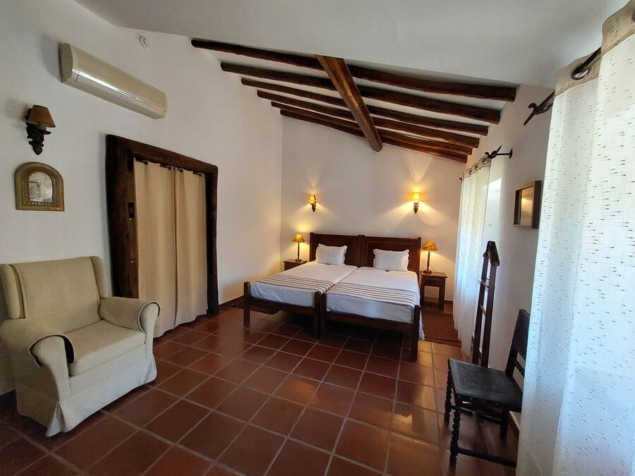 A room with two beds, a sofa, a chair, and a wooden ceiling.