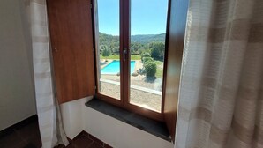 Une pièce dotée d’une grande fenêtre donnant sur une piscine et un jardin aménagé.
