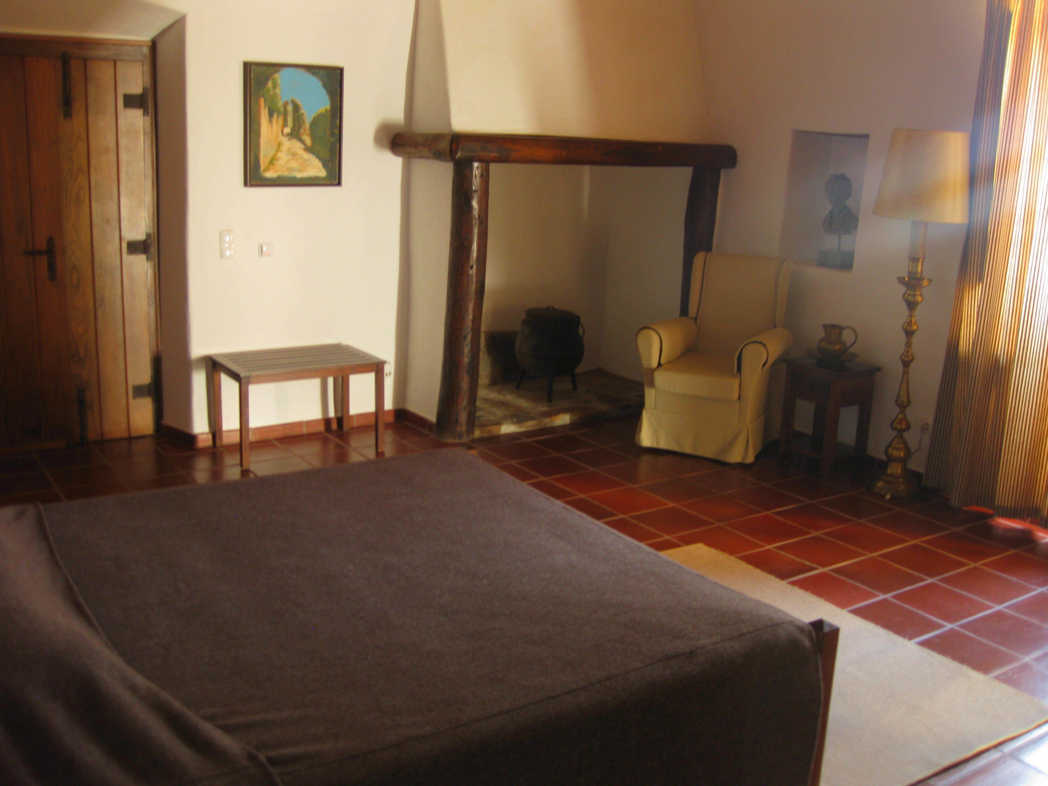 A room with a bed, a chair, a small table, and a lamp.