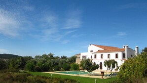Une villa blanche avec un toit en tuiles, une piscine et un jardin bien entretenu.