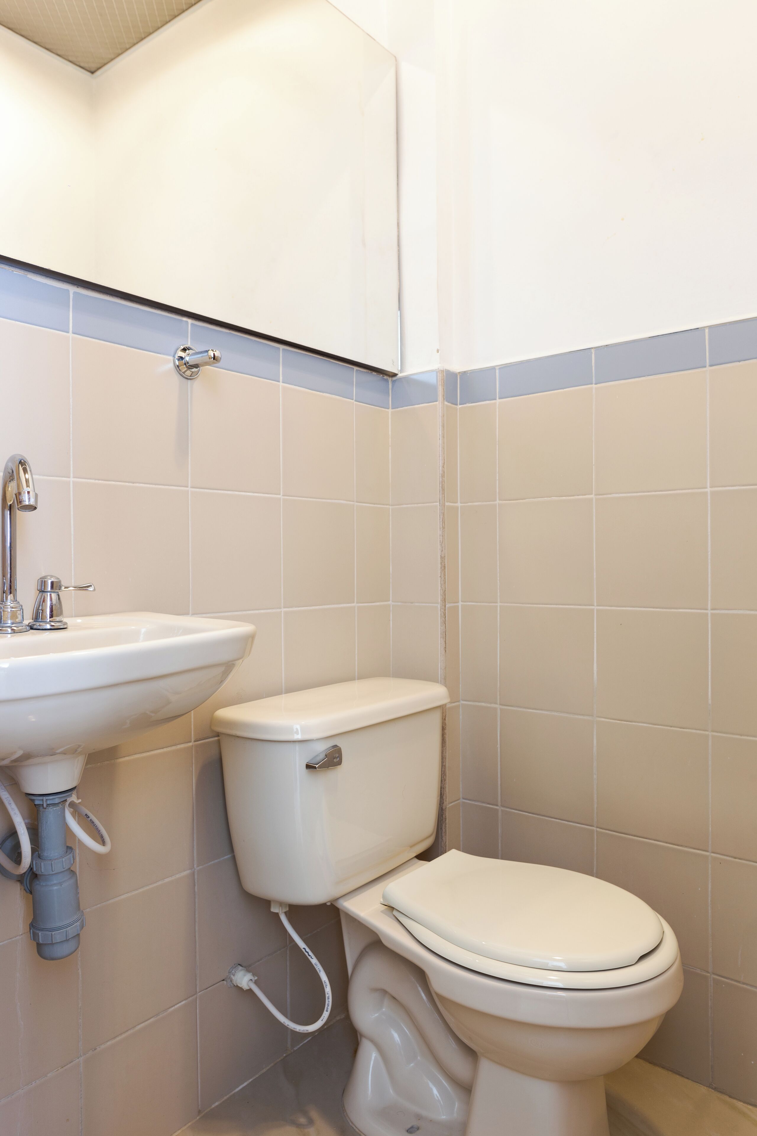 Baño con lavamanos, inodoro y paredes de azulejos.