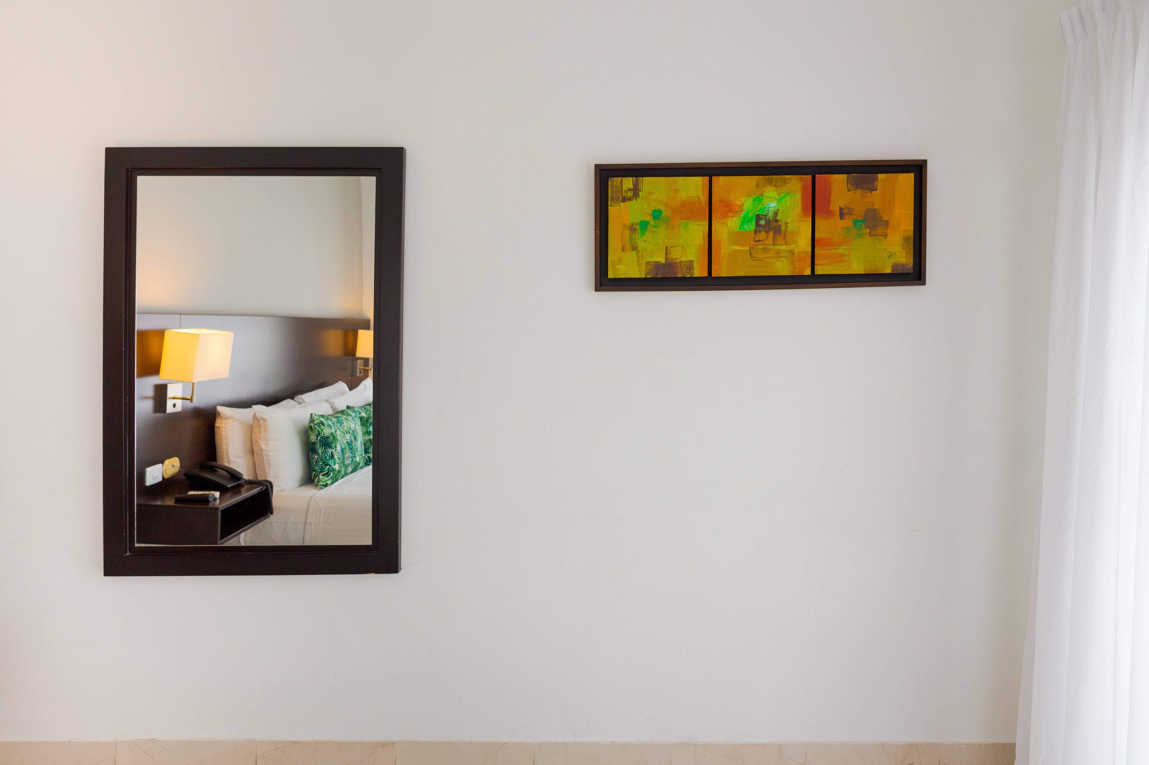 Una habitación de hotel con cama, mesita de noche, lámpara y espejo.