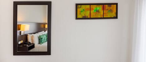 Una habitación de hotel con cama, mesita de noche, lámpara y espejo.
