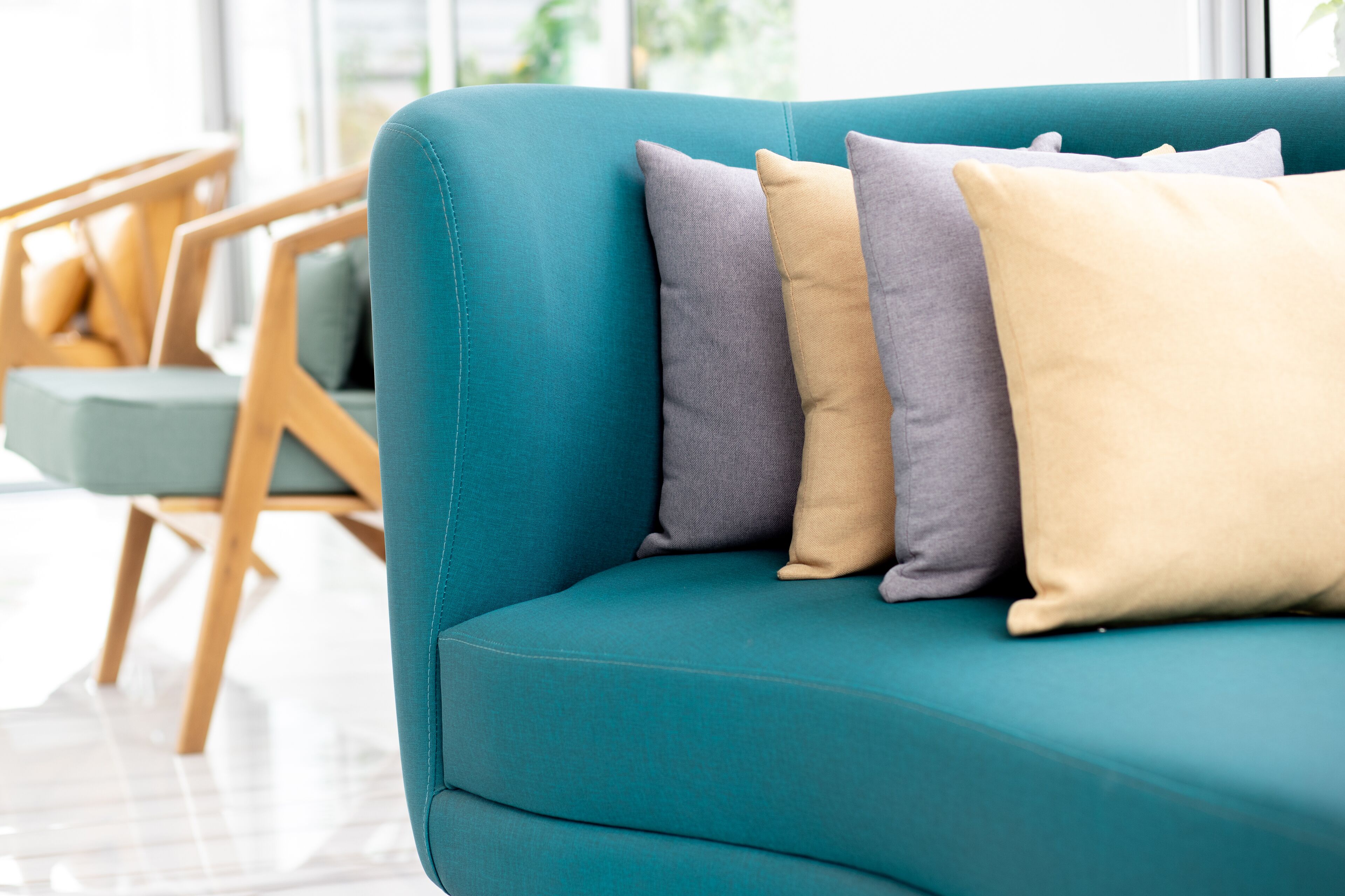 A teal sofa with four cushions in different shades.