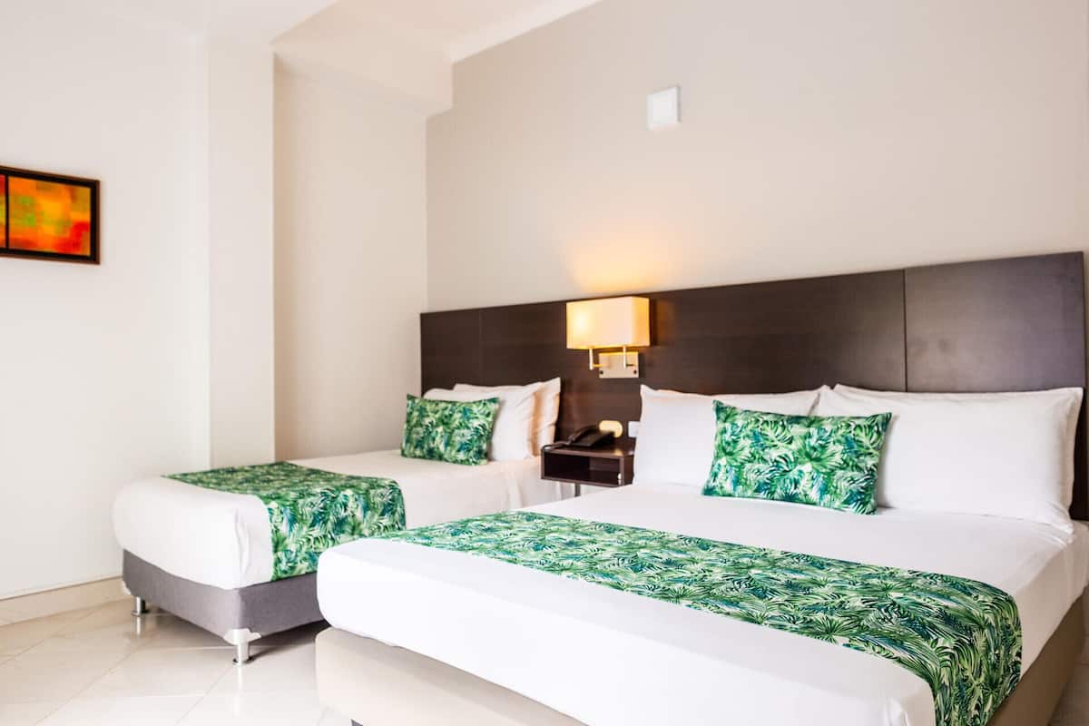 A hotel room with two beds, a nightstand, a lamp, and a painting on the wall.