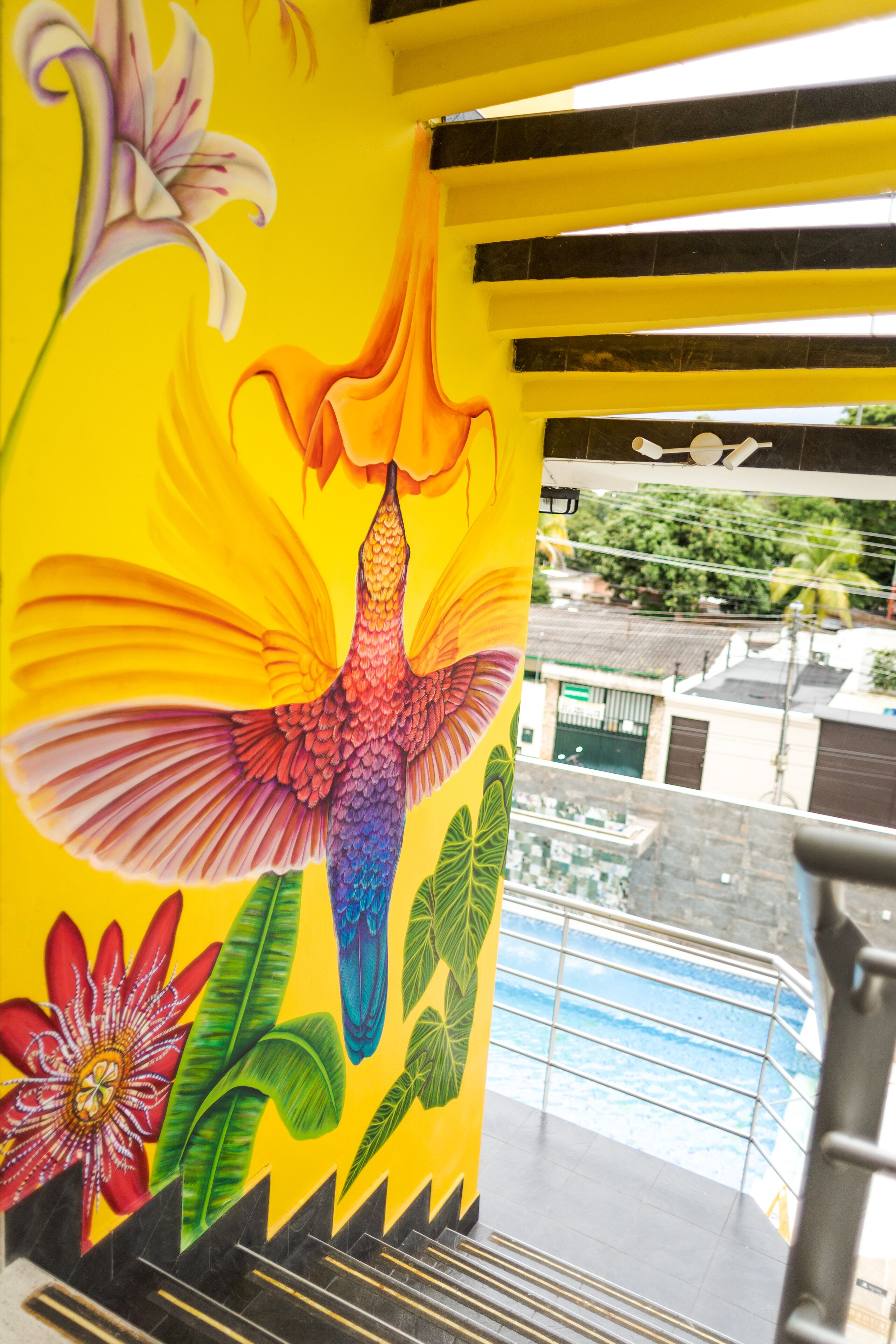 A vibrant mural with a bird and flowers on a building's exterior wall.