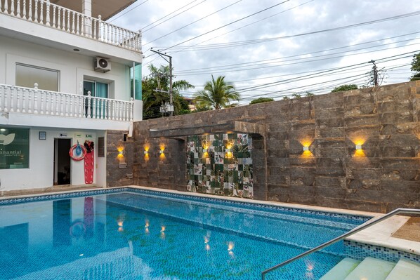 A swimming pool with a stone wall and a balcony.