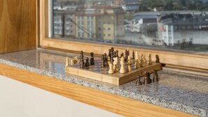 A chessboard on a wooden table inside a room with a skylight, overlooking a cityscape. - Apartamentos Portazgo (A Coruña)