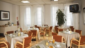 A hotel dining area with multiple tables, chairs, and a large potted plant. - Apartamentos Portazgo (A Coruña)