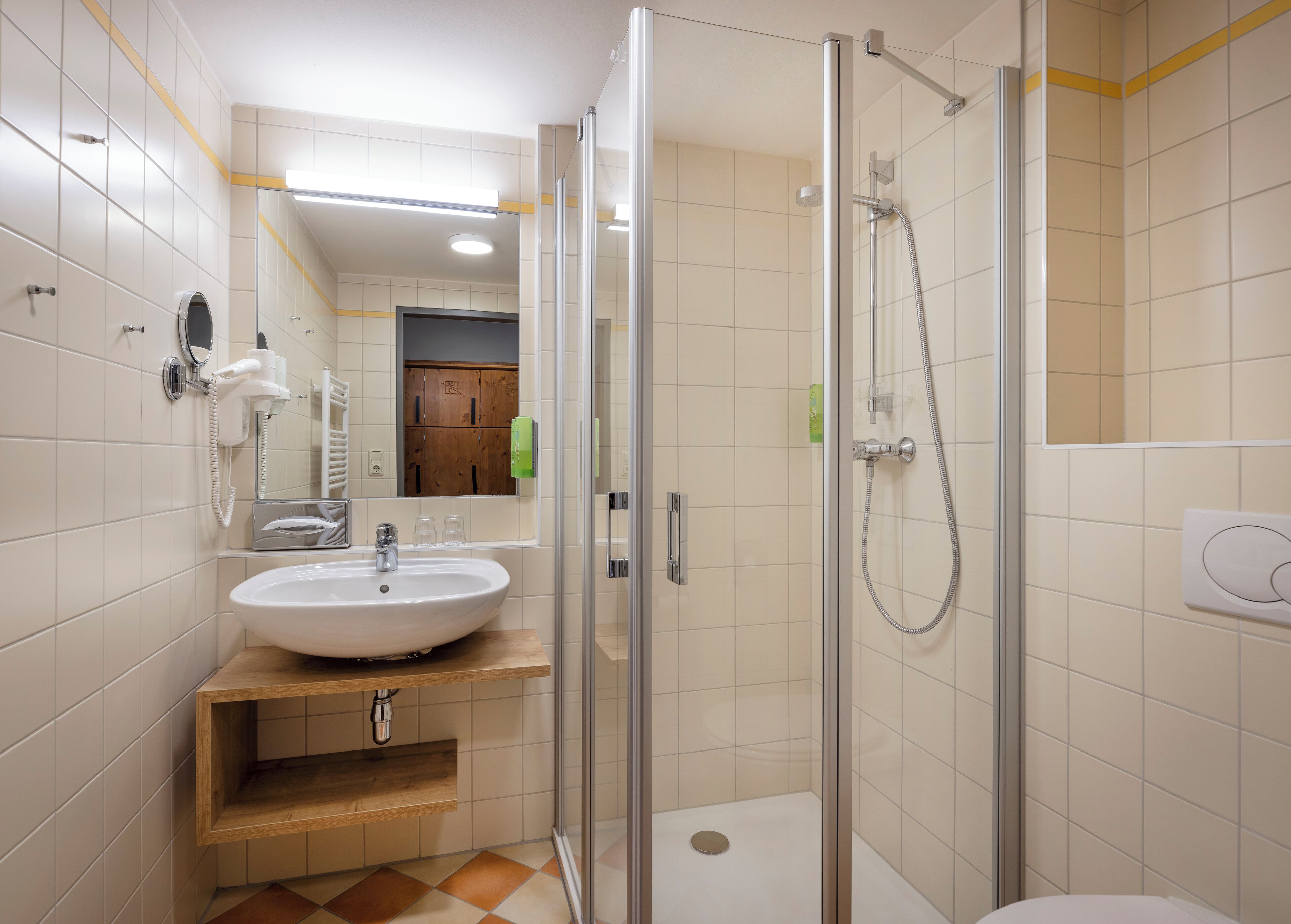 Een moderne badkamer met een glazen douchecabine, een wastafel met spiegel en een toilet.