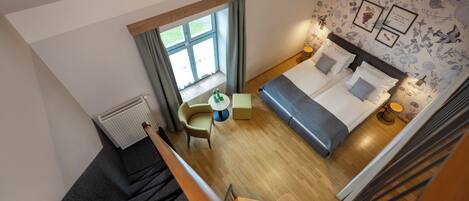 Habitación de hotel con cama, escritorio, silla y ventana con cortinas.