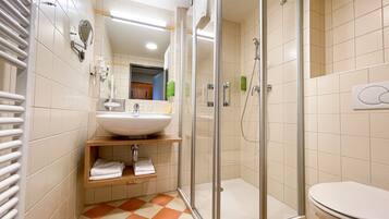 Un bagno moderno con doccia vetro, lavandino bianco e water.