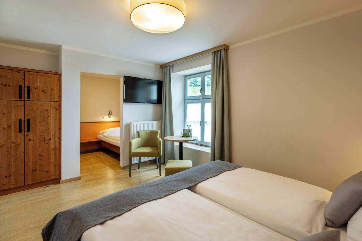 Una habitación de hotel con una cama, una silla, una mesa y un televisor.