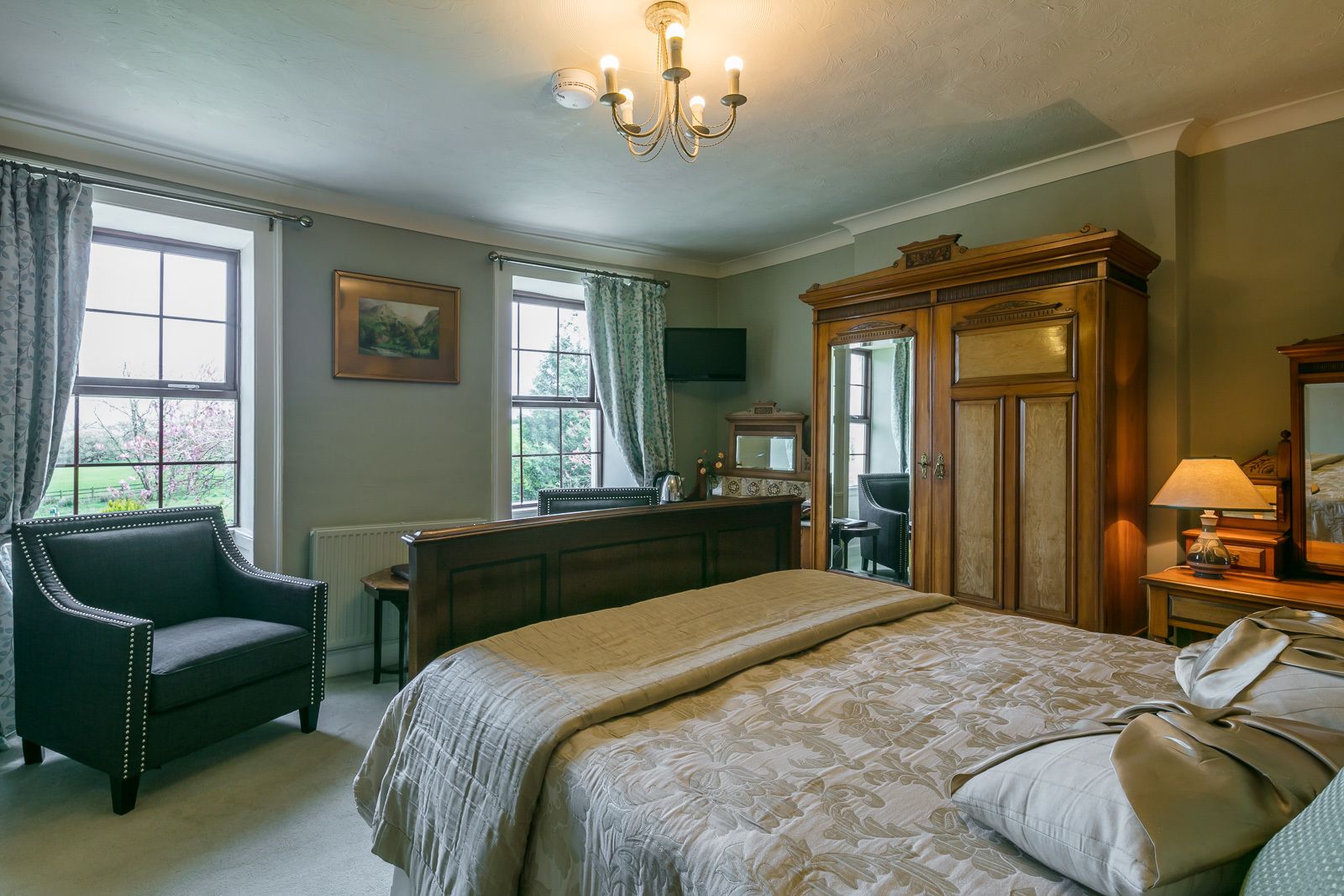 A bedroom with a large bed, a dresser, a chair, and a mirror.