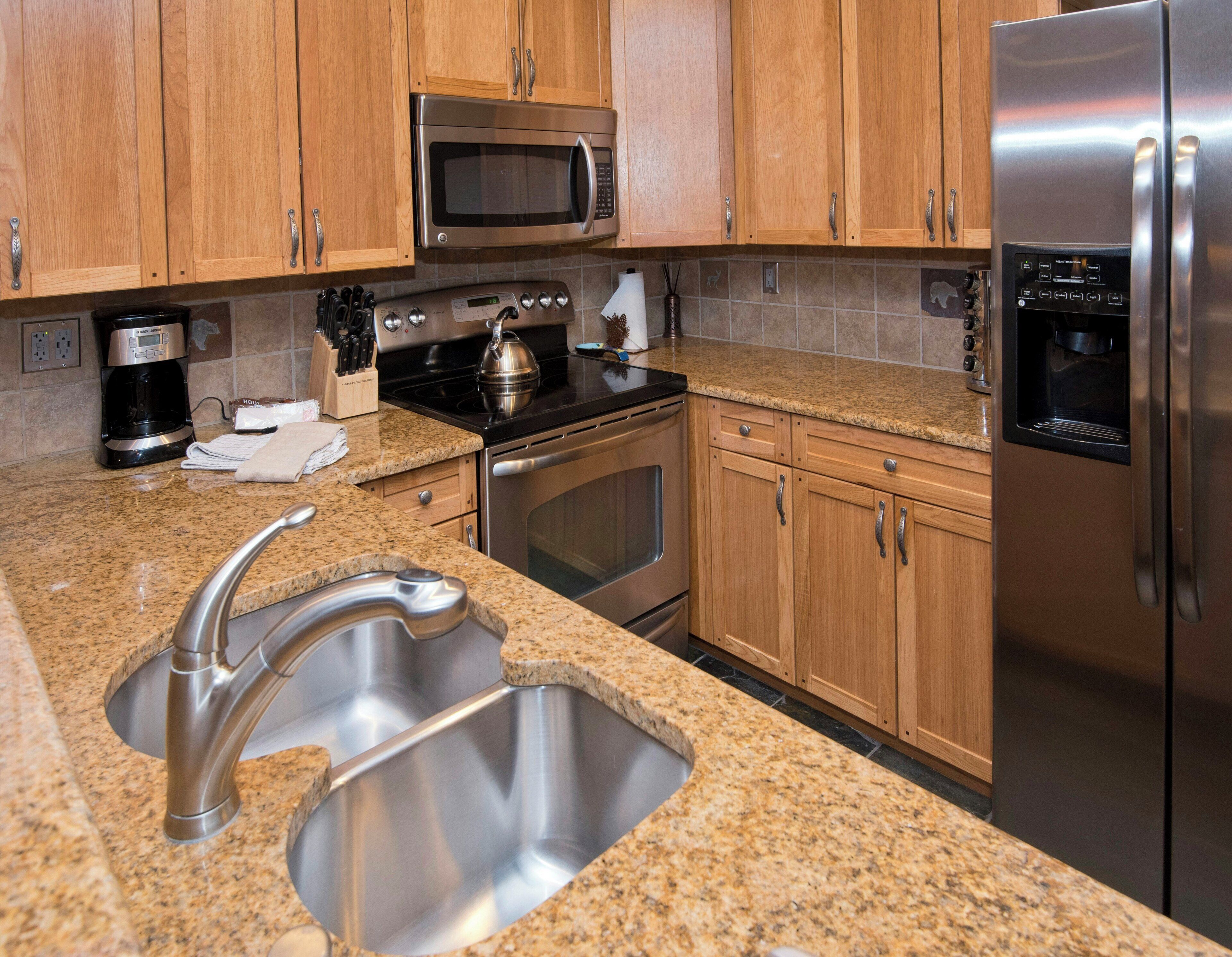 A kitchen with granite countertops, stainless steel appliances, wooden cabinets, and a built-in oven.