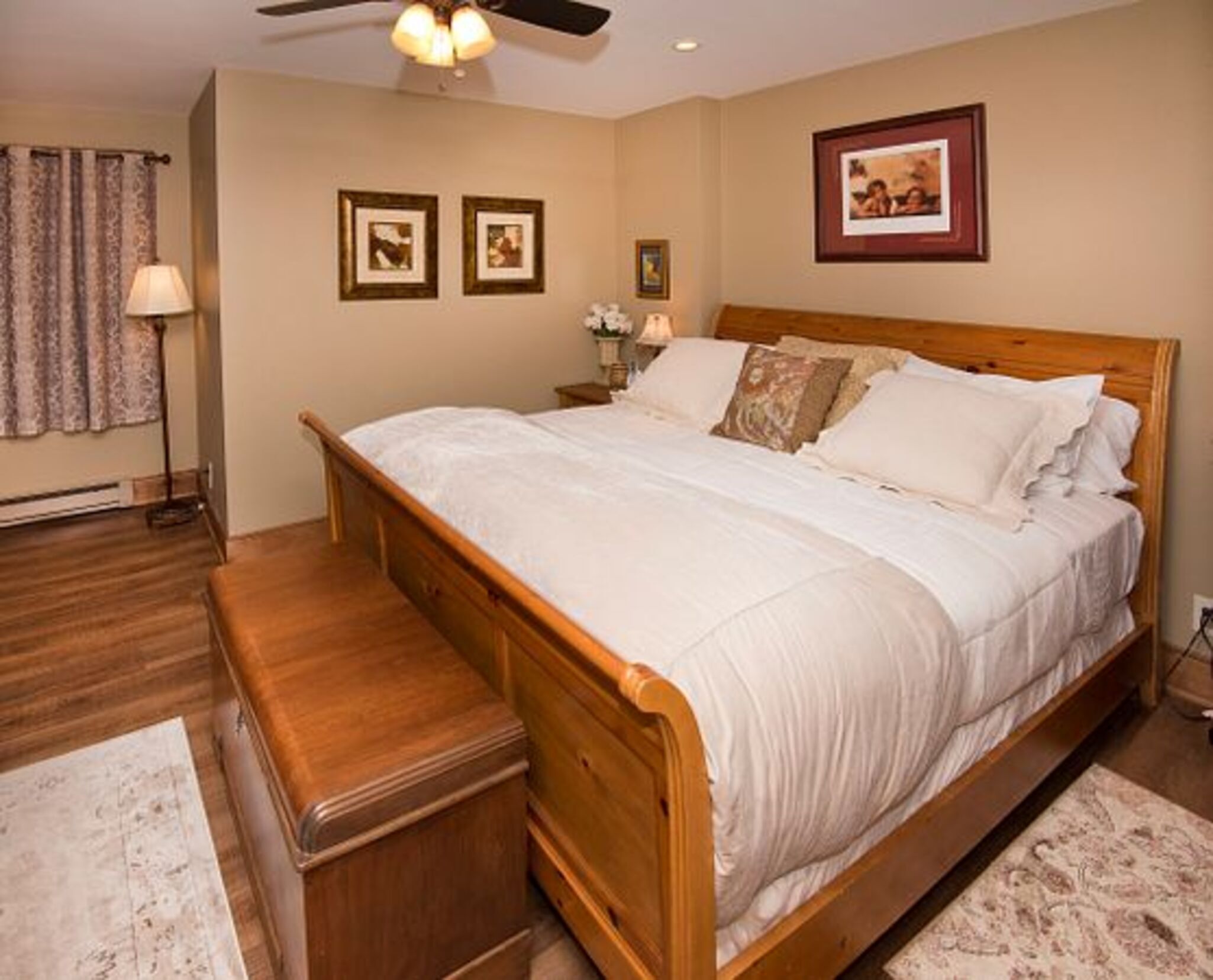 A bedroom with a wooden bed, a nightstand, a lamp, and framed pictures on the wall.