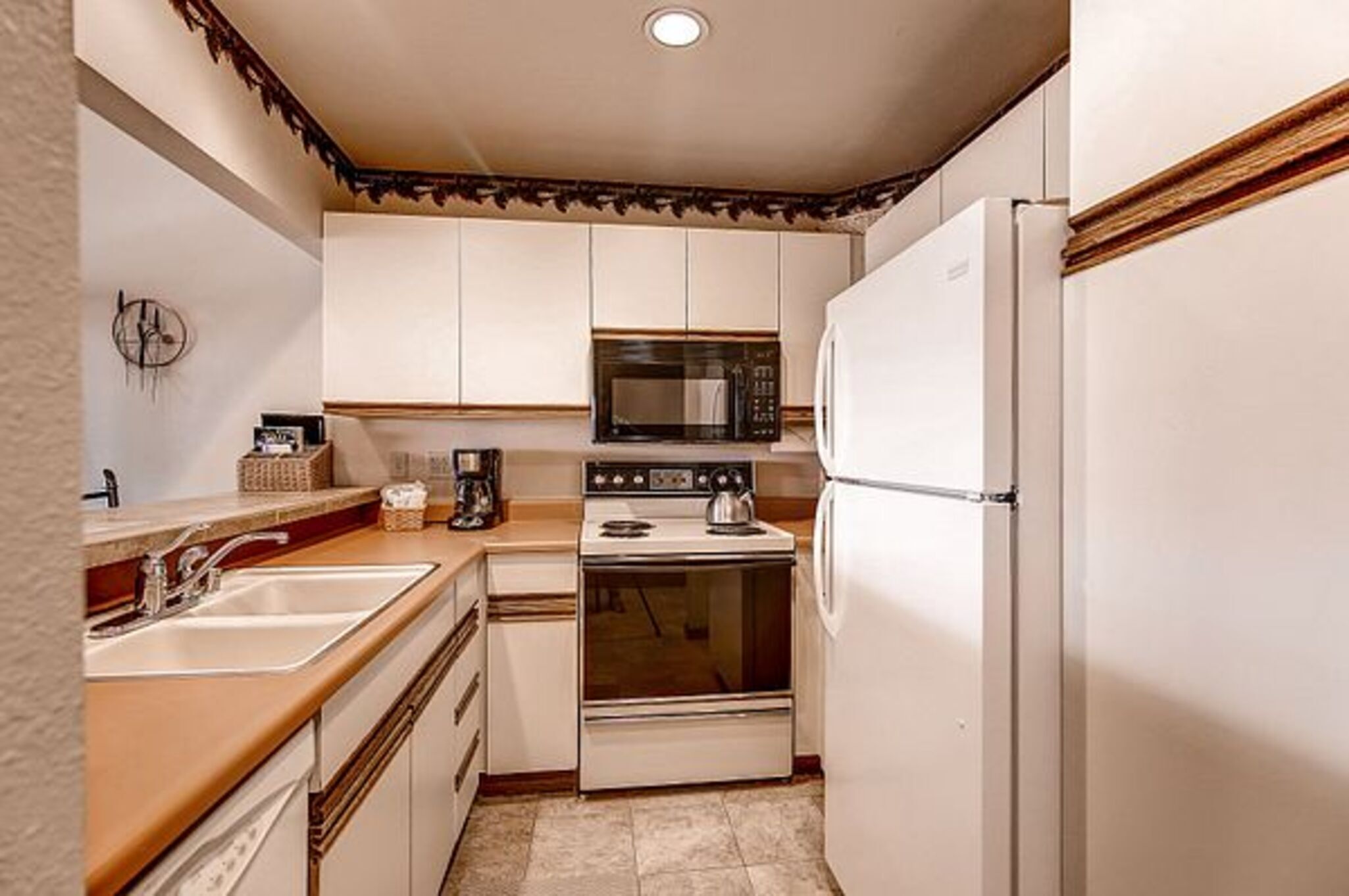 A compact kitchen with white cabinets, a microwave, an oven, and a refrigerator.