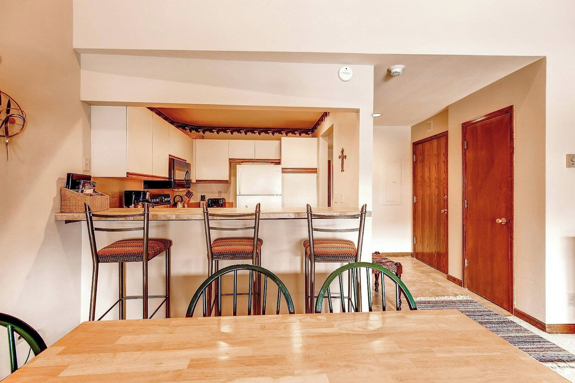 A compact kitchen with a central island, four chairs, and a dining table.