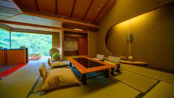 A tatami mat room with a low table, cushions, and a view of greenery outside.
