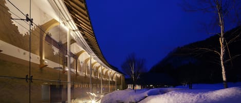 A building with a glass facade and a snow-covered landscape at night.