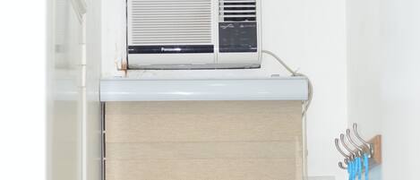 A bathroom with a white sink, a towel rack with blue towels, and a Panasonic air conditioner mounted above the sink.