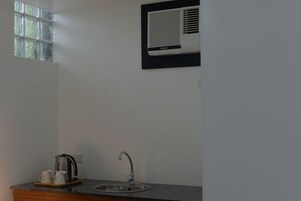 Un baño con lavamanos, ventana y aire acondicionado de pared.