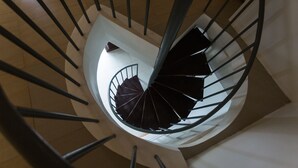 Una escalera de caracol con diseño moderno, que cuenta con un pilar central y barandales a ambos lados.