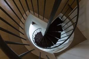 Una escalera de caracol con diseño moderno, que cuenta con un pilar central y barandales a ambos lados.