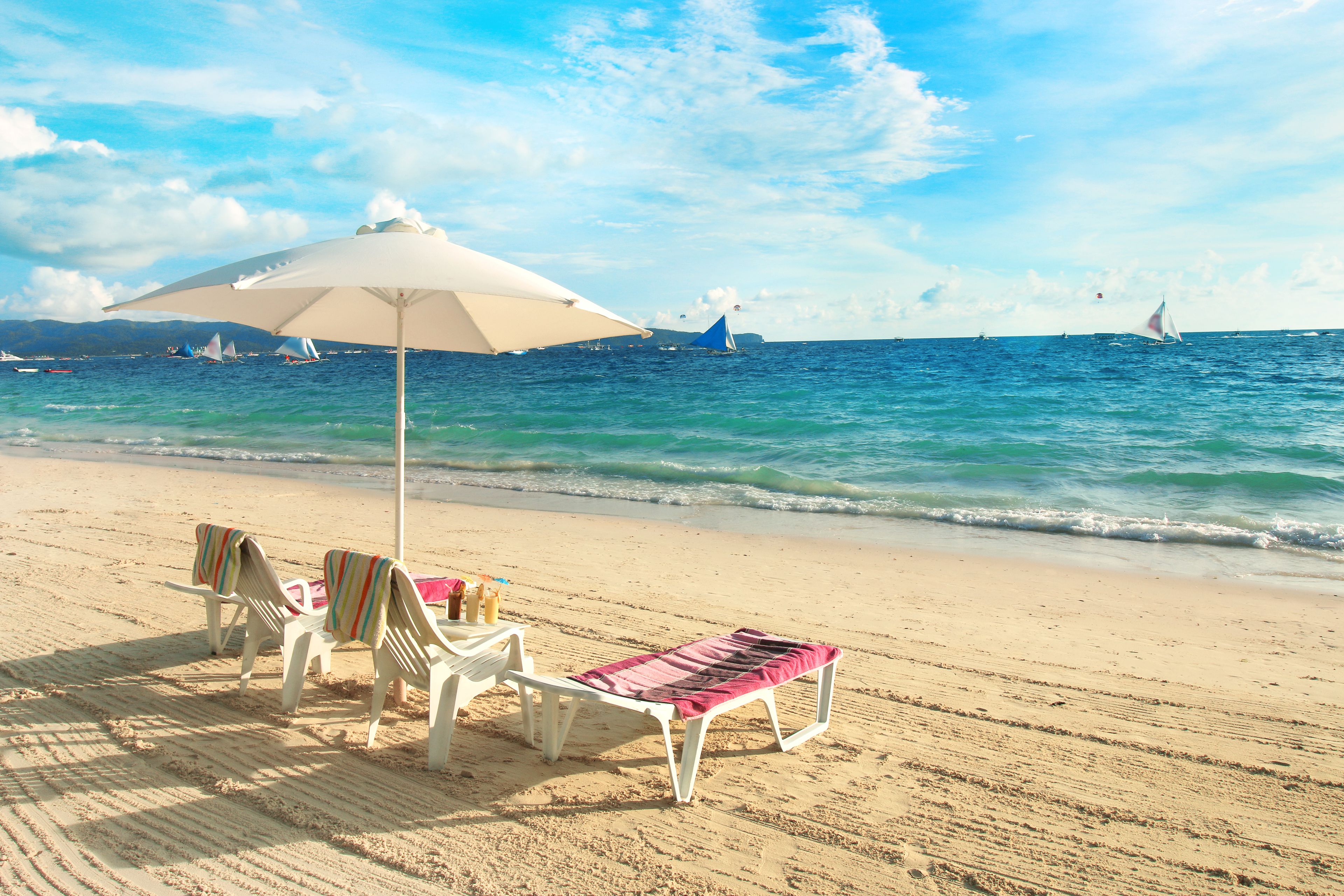 على الشاطئ، رمال بيضاء، كراسي للتشمس، مظلات الشاطئ