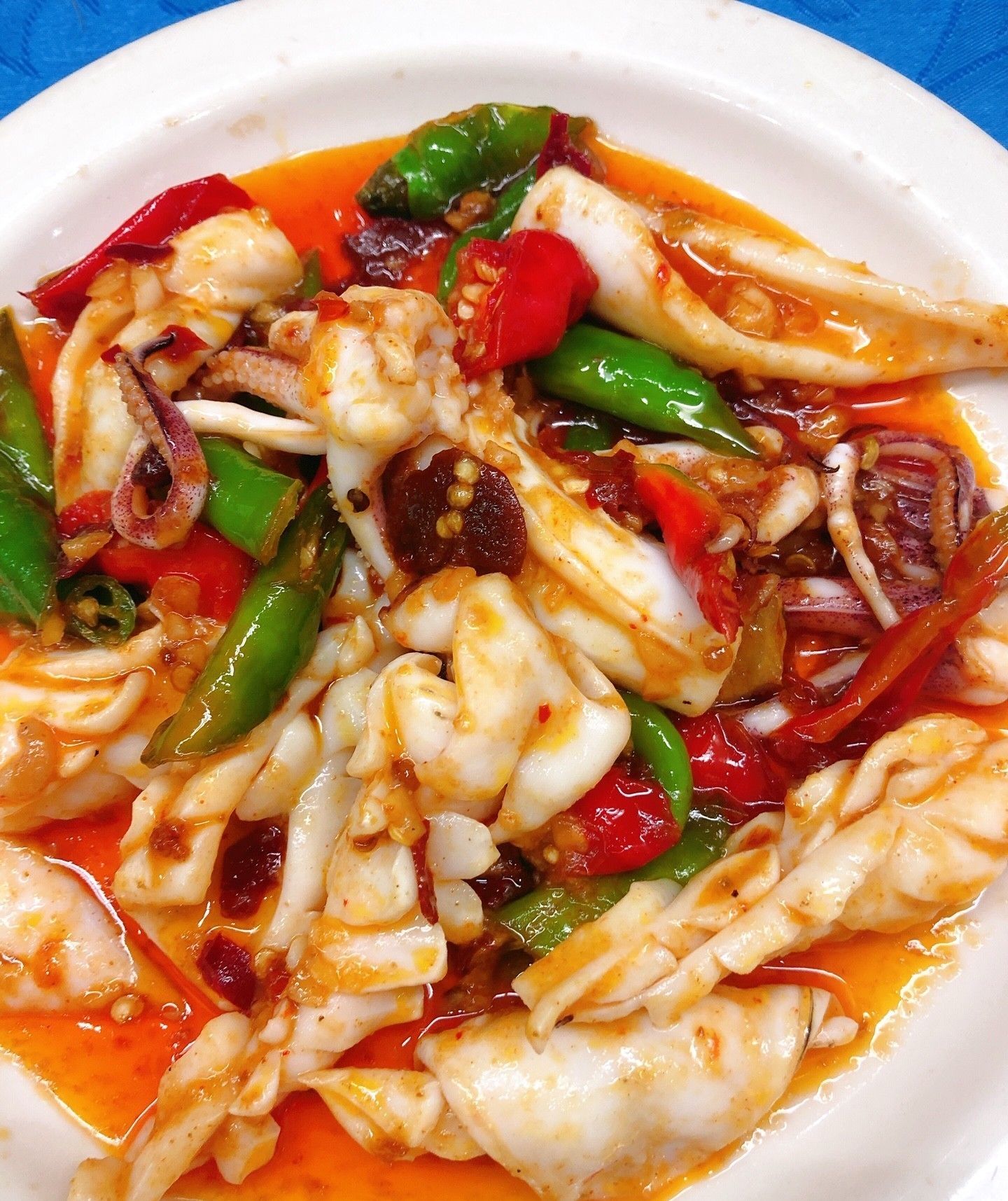 Un plat composé de calamars, de poivrons et d’oignons, le tout nappé d’une sauce rouge.